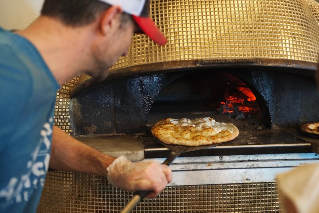 Chef cooking pizza in a wood-fired oven