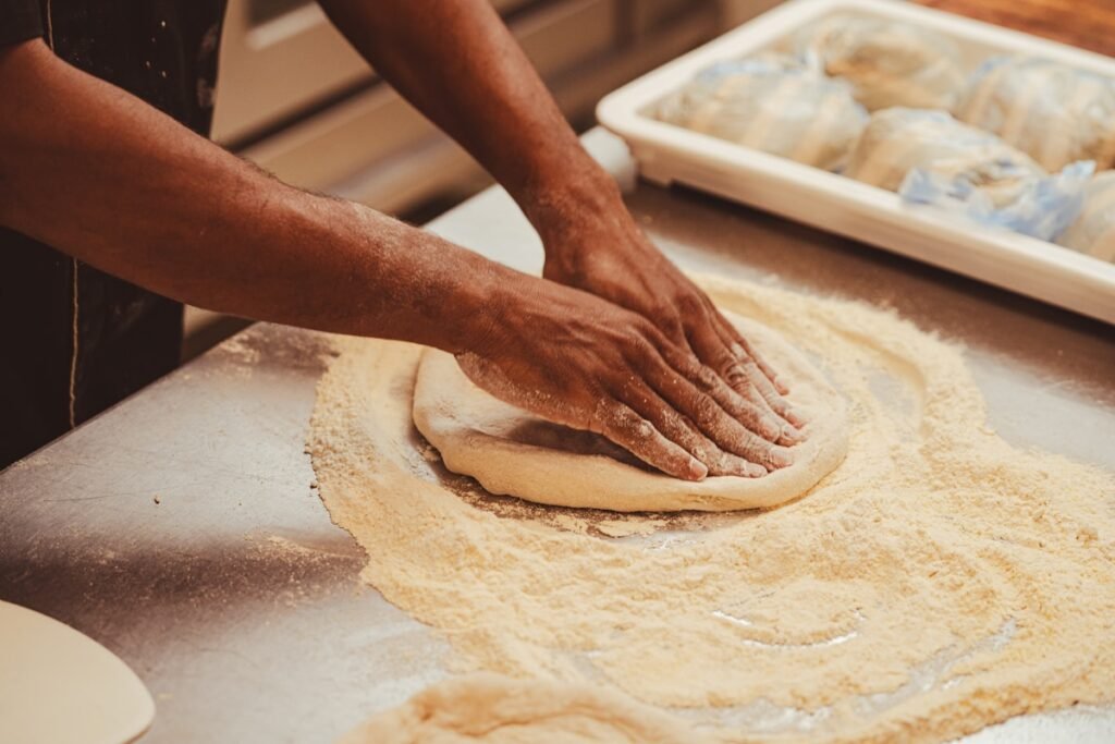 How to Make Pizza Dough Without a Mixer (By Hand) Hands kneading pizza dough on a table