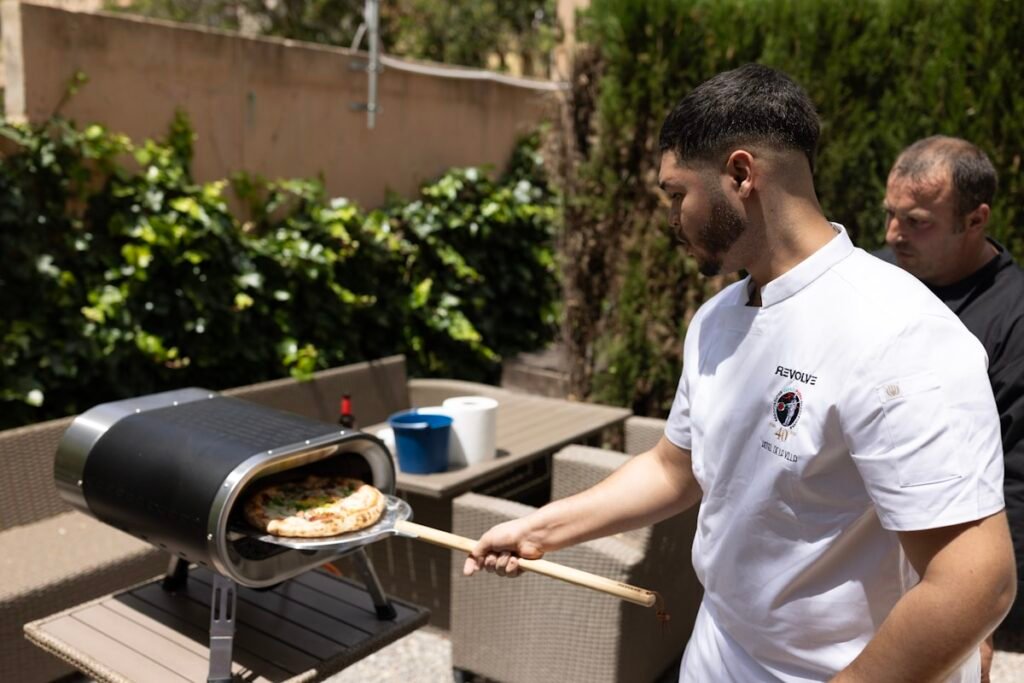 Man grilling pizza on an outdoor pizza oven