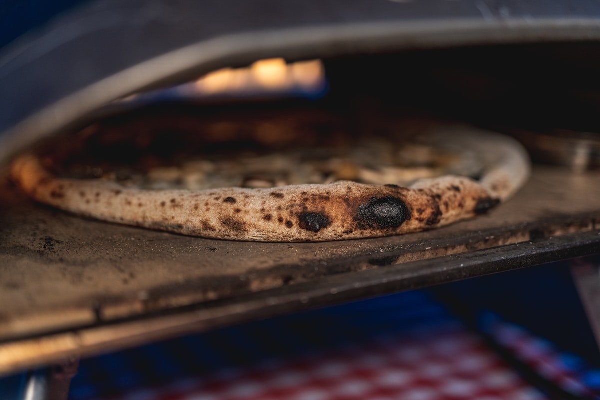 Close-up of pizza cooking in a wood-fired oven