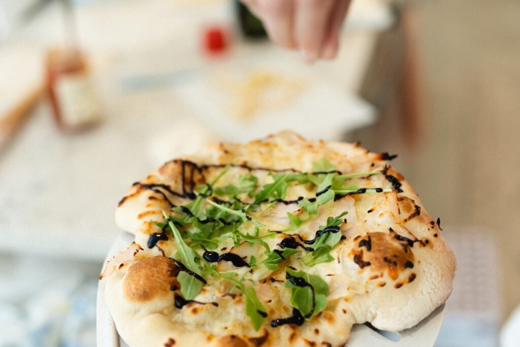 Best Pizza Peels for Wood-Fired Ovens Person holding a pizza on a wooden pizza peel