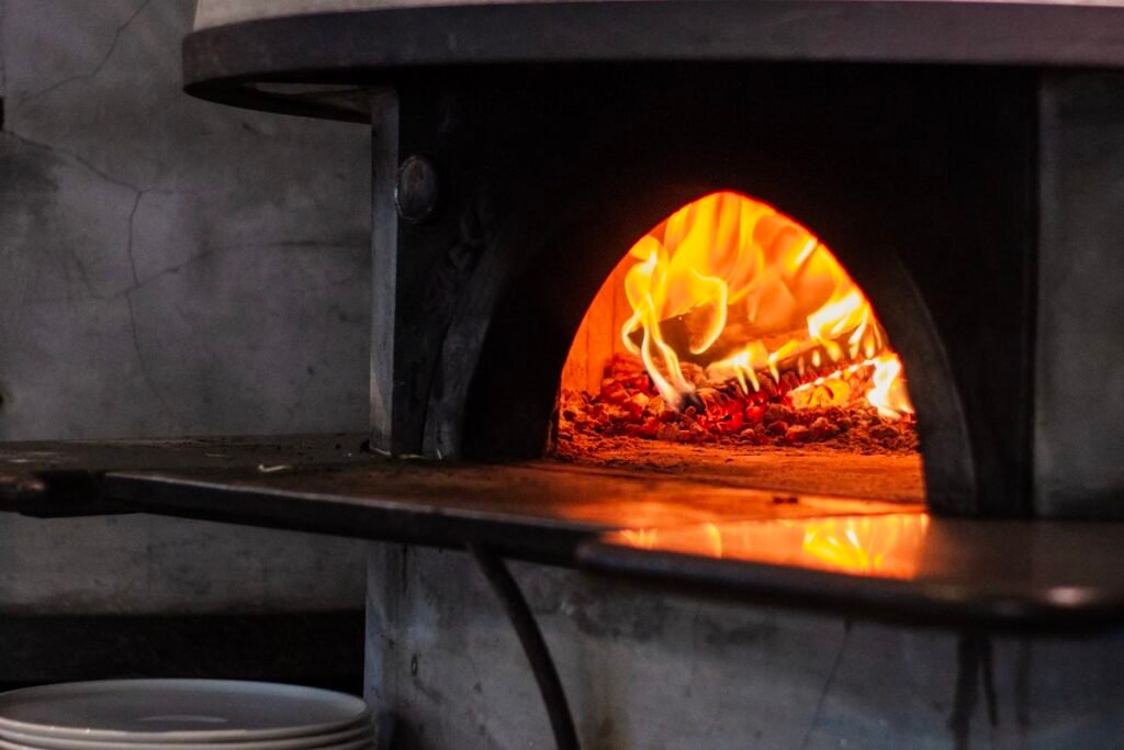 Ooni vs Gozney: Which Pizza Oven Brand Is Better? Wood-fired pizza oven with pizza cooking inside