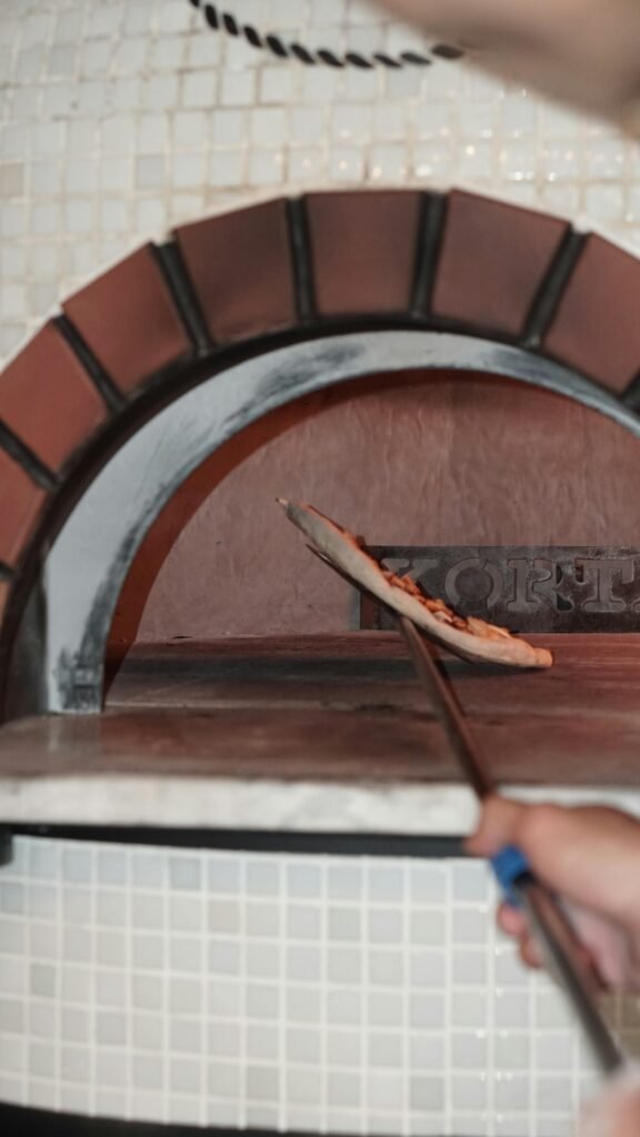 How to Clean a Pizza Stone (Without Wrecking It) Person pulling pizza from oven on stone