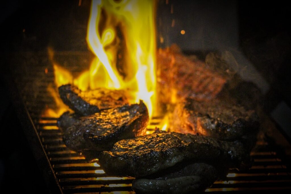 What Else Can You Cook in a Pizza Oven? 15 Ideas Beyond Pizza Steaks cooking over open flames on a grill